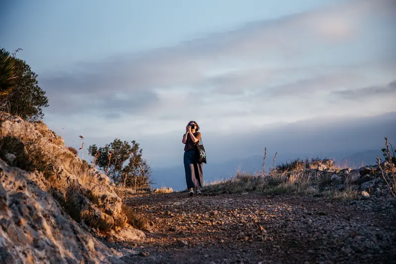 Two people silhouetted on the Monte Gallo trail at dusk