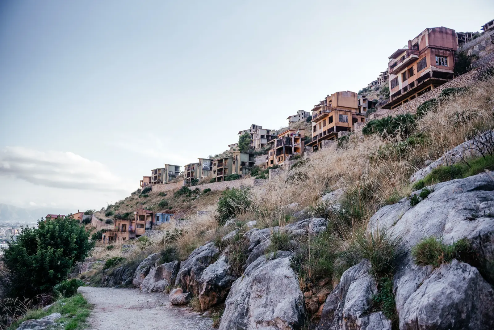 Rows of abandoned, unfinished villas climbing the slope of Pizzo Sella above the trail