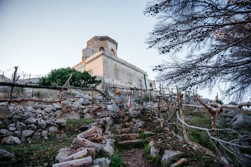 The Semaforo dell'Eremita rising behind a terraced stone garden with wooden trellises